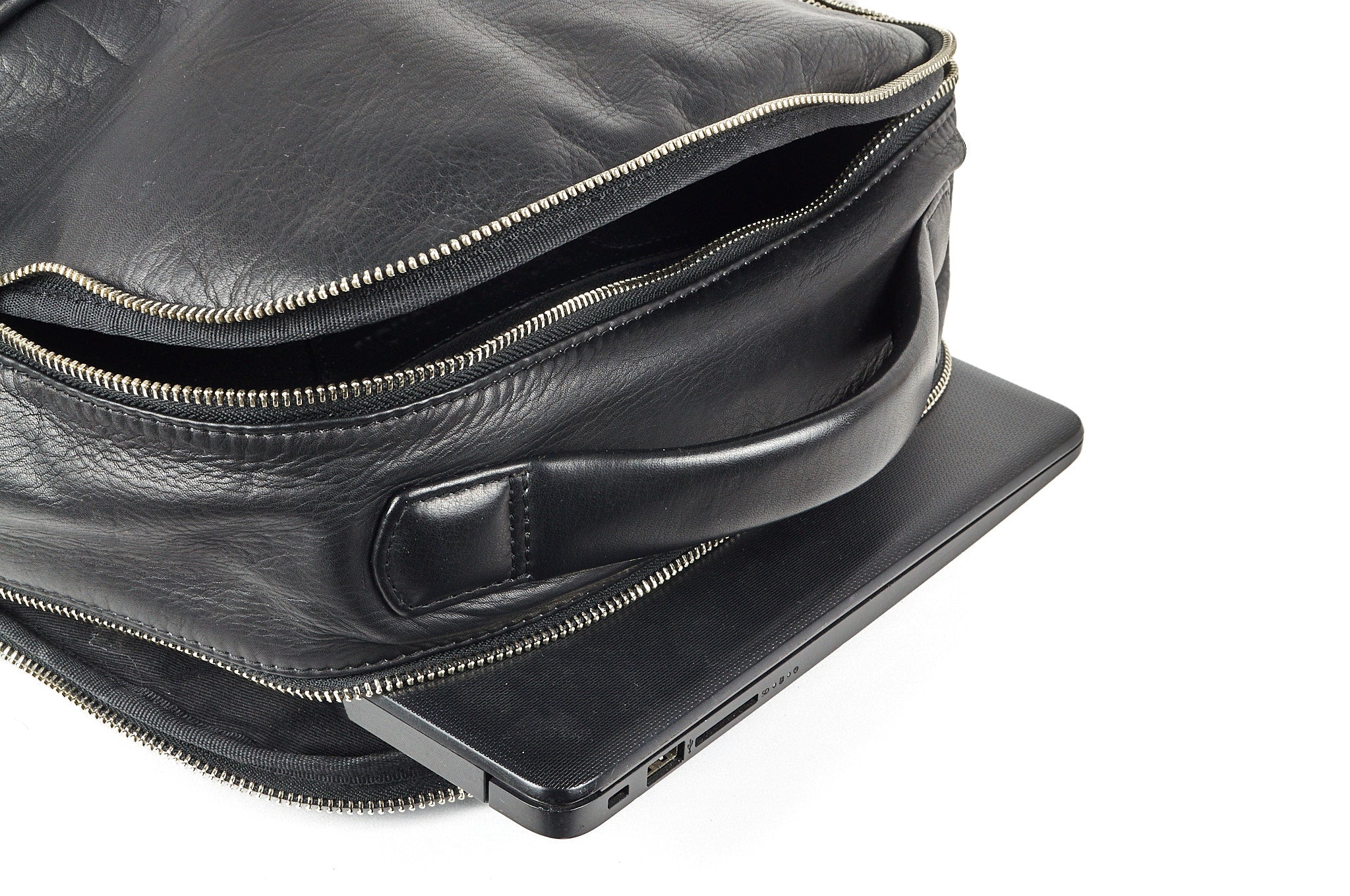 Detalle del morral de cuero negro ROCKY acostado, resaltando manija y refuerzos portacomputador.