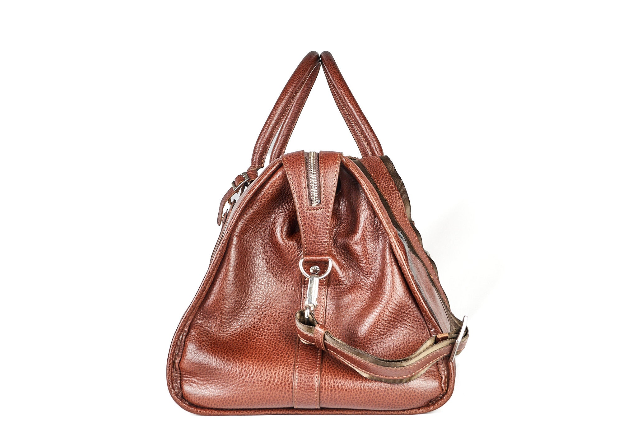 Bolso de viaje Maverick en cuero cognac, vista lateral mostrando cierre y estructura.
