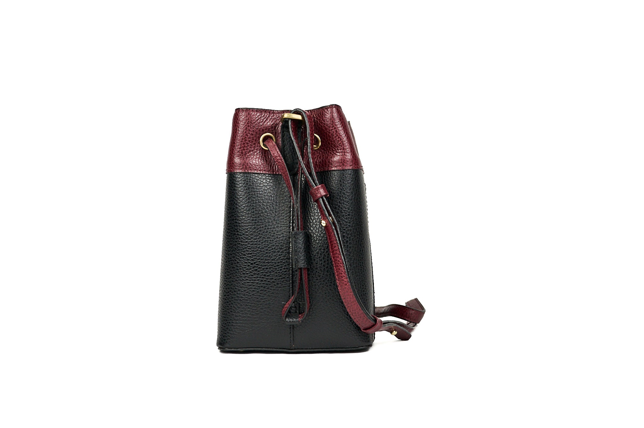 Vista lateral del bolso bucket VALDÉZ en cuero negro y vino tinto, con correa para el hombro.