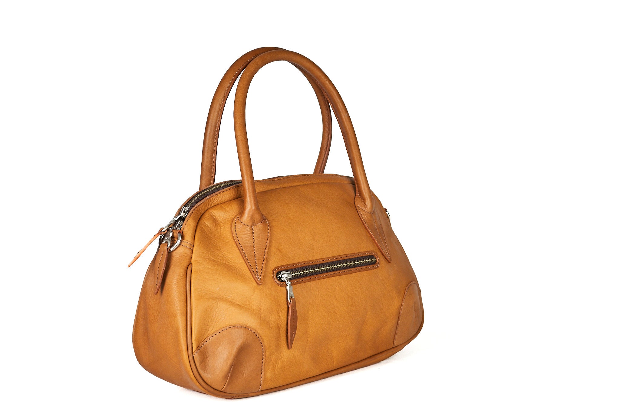 Vista lateral del bolso FRIDA en cuero color miel, mostrando el grosor del bolso y su estructura y bolsillo posterior.