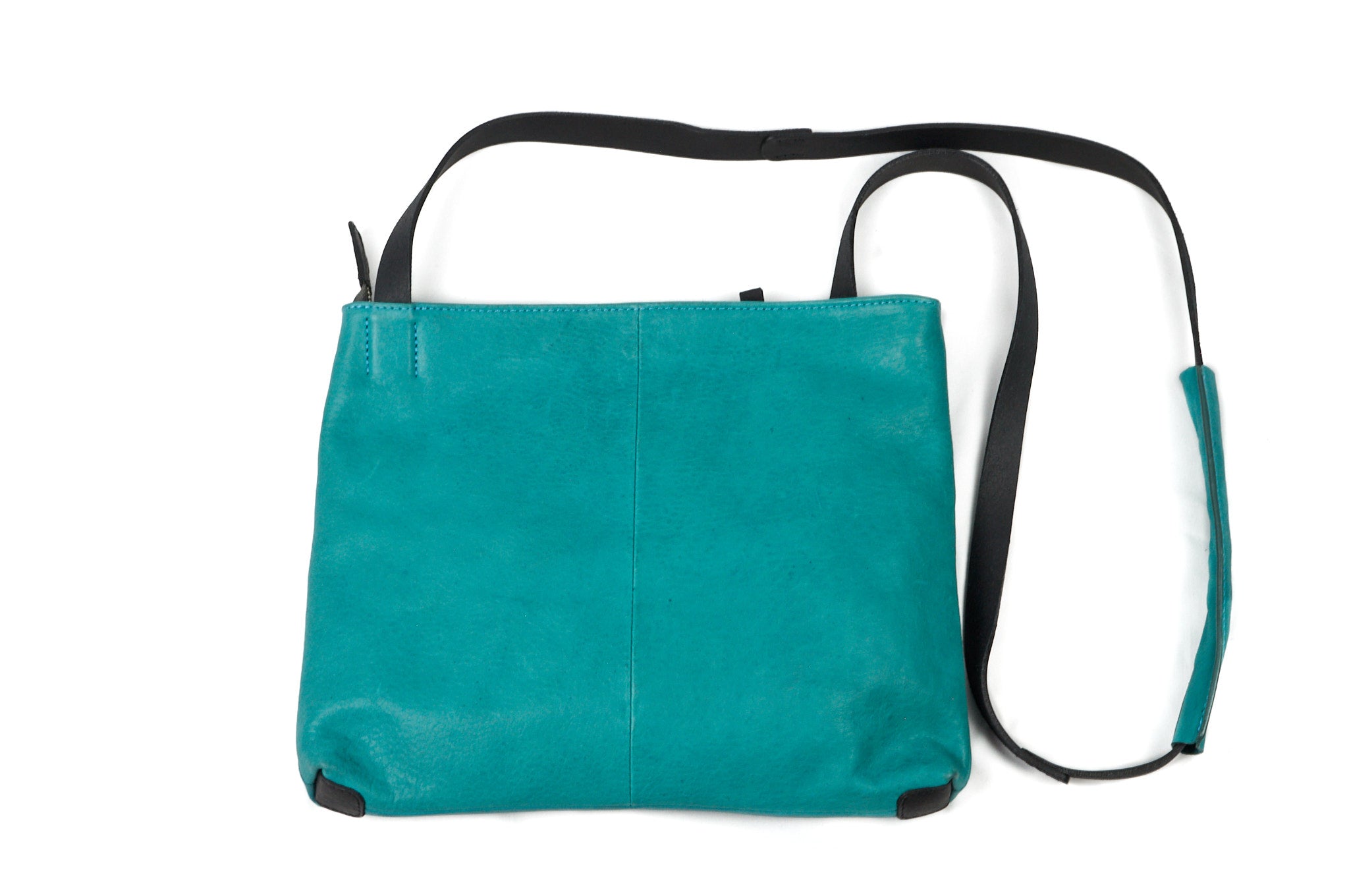 Vista lateral del bolso BLUE en cuero turquesa, resaltando su forma ligera y correa ajustable.
